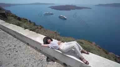 女人享受放松说谎墙唠唰��圣托里尼岛景观视图火山巡洋舰船火山口
