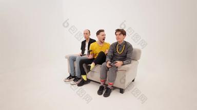 快乐赢得游戏的家伙黄色的衬衫玩视频游戏朋友坐着白色沙发孤立的白色背景的家伙反应赢得失去游戏概念镜头