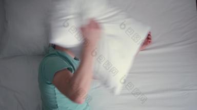 年轻的男人。说谎床上快睡着了打扰睡眠封面枕头醒来白色床上用品绿松石蓝色的t恤前视图