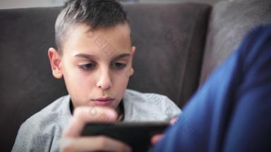 十几岁的男孩智能手机首页玩视频游戏