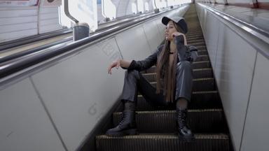 美丽的年轻的女孩坐在攀爬<strong>自动扶梯</strong>模型提出了相机地铁美丽的年轻的模型爬退出地铁坐着步骤<strong>自动扶梯</strong>