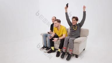 庆祝胜利玩控制台视频游戏朋友坐着白色沙发孤立的白色背景的家伙反应赢得失去兴奋朋友玩视频游戏首页镜头
