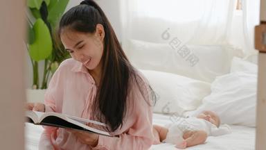 年轻的亚洲妈妈。读书坐床<strong>上新</strong>生儿婴儿睡眠背景