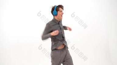 有节奏的舞蹈听音乐有趣的跳年轻的男人。灰色体育装听音乐穿蓝色的无线耳机有趣的跳舞年轻的的家伙孤立的白色背景镜头