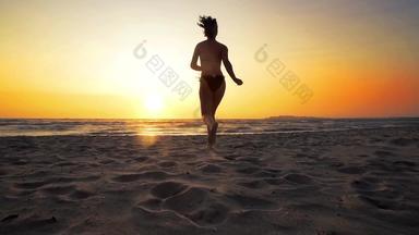 性感的浅黑肤色的女人女人完美的身体运行海滩日落电影慢运动