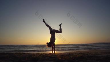 年轻的运动女人平衡<strong>倒立</strong>锻炼海滩日落慢运动