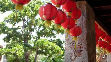 纸灯笼破旧的建筑红色的纸灯笼挂天花板饱经风霜的混凝土寺庙建筑阳光明媚的一天多汁的绿色植物东方国家传统的装饰