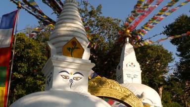 色彩斑斓的雕塑寺庙阳光白色石头舍利塔雕塑色彩斑斓的点缀花环祈祷旗帜明亮的阳光尼泊尔