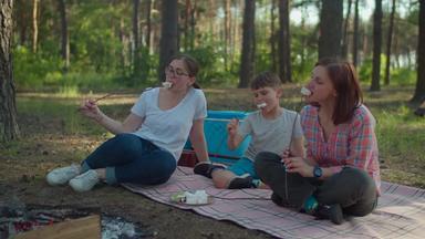 母亲儿子吃棉花糖棒女性男孩夏天野营假期森林慢运动替身拍摄
