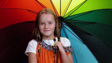 微笑女孩母亲的背心裙珠子曲折开放明亮的多色的伞高加索人孩子相机微笑黑色的背景