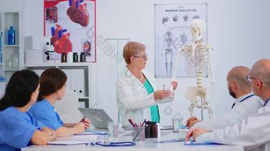 上了年纪的女人医生显示工作人的手骨架模型