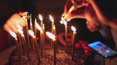 生日蛋糕蜡烛关闭女手燃烧生日蜡烛聚会，派对蛋糕甜蜜的生日庆祝活动女手光蜡烛火更轻的火焰