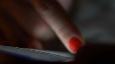 玩智能手机黑暗女手指现代智能手机触屏显示浏览互联网电话