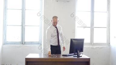 办公室工人伸展运动桌子上时间休息英俊的年轻的男人。伸展运动工作办公室年轻的商人放松白色工业风格办公室
