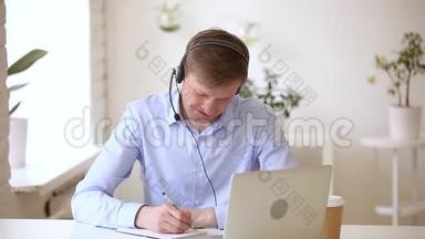 微笑商人戴着耳机在网上学习做笔记