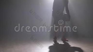 近镜头篮球运动员`双腿在烟雾弥漫的黑暗房间里打球