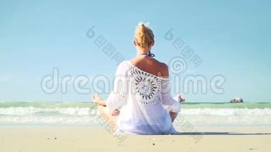 年轻的金发女人在海滩上做瑜伽