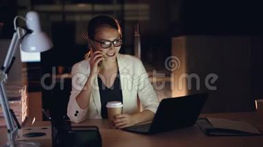有魅力的女企业家正在用手机和笔记本电脑在深夜办公。 现代