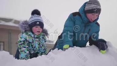 孩子们在雪山上玩耍，扔雪和。 晴朗的霜天。 新鲜空气中的乐趣和游戏。