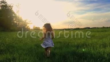 日落后拍摄<strong>的</strong>可爱<strong>少年</strong>女孩穿着连衣裙<strong>奔跑</strong>在绿色草地上。 120英尺，慢速运动。