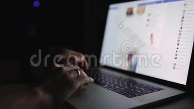 男人正在工作打字，在深夜在家里的办公室使用笔记本电脑。 社交媒体face book浏览