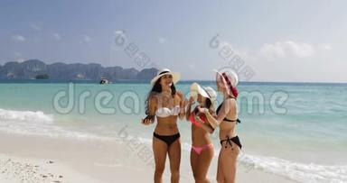 沙滩上的女孩在手机上自拍，夏日假日里比基尼和草帽里的快乐女人