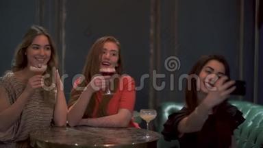 三个可爱的女孩坐在咖啡馆或餐馆里，摆着漂亮的姿势，为社交网络拍照自拍