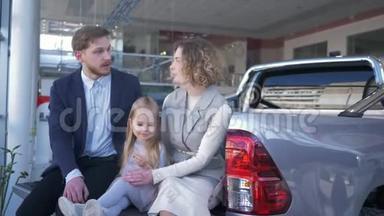 汽车沙龙，带孩子的年轻家庭选择汽车，坐在汽车后备箱交流