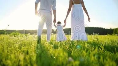 一家人在公园散步，小女儿迈出了第一步。 全都穿着白色的衣服，在夕阳下。