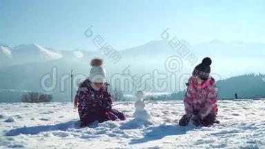 穿着户外运动的孩子在雪地里玩耍时堆起小雪人，背景是群山