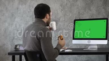 办公室里的商人在吃早餐，午餐，在Mac电脑上看东西。 绿色屏幕模拟