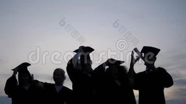 庆祝教育毕业学生成功学习理念。 学生在空中抛帽子的剪影。