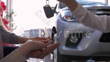 汽车业务，车主家属手拿钥匙背景汽车特写在销售中心