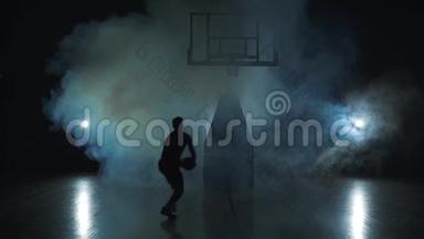 篮球跳跃-一个男人黑暗的轮廓。 <strong>烟雾</strong>中的黑色背景。