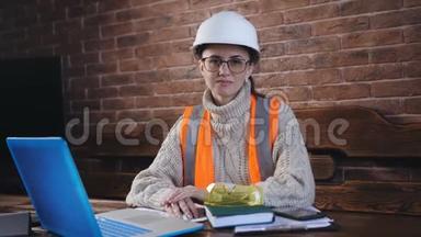 工作场所<strong>女工</strong>程师的肖像。 <strong>女工</strong>程师戴着头盔和防护背心坐在哈工作桌上。
