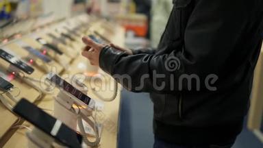 一个年轻人`商店里挑选一部新手机的特写镜头。 他在尝试它的运作方式