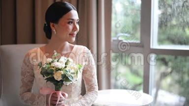 亚洲新娘，穿着蕾丝连衣裙，捧着美丽的白色婚纱，闻着美丽的白色婚纱