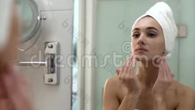 面部皮肤护理。 女人在浴室里涂抹<strong>护肤霜</strong>