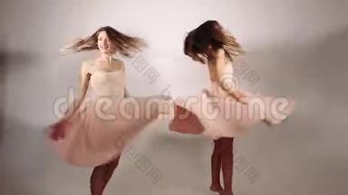 女孩子绕着裙子转，卷着裙子，从风和女孩的运动中升起。 两个漂亮可爱的女孩