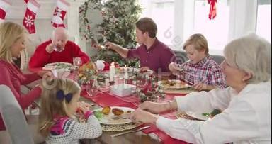 镜头追踪到一个大家庭围坐在桌子旁享受<strong>圣诞大餐</strong>