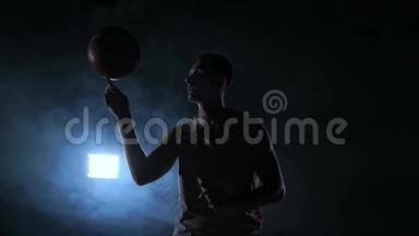 近镜头篮球运动员旋转球在他的<strong>手指</strong>，黑暗的雾室与泛光<strong>灯</strong>