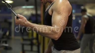 一个人在健身房里<strong>努力</strong>工作，用一只手臂快速地拉下，完成锻炼