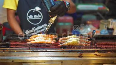 亚洲街头美食，亚洲传统菜肴。 海鲜虾在烤架上，厨师烤他们的燃烧器。 夜食市场