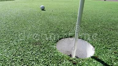 白色高尔夫球<strong>击打</strong>旗棒，在放绿色球时掉进洞里