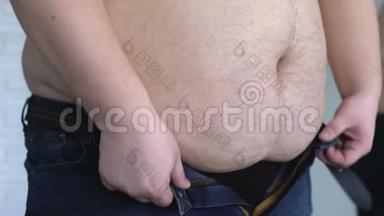 超重的人把牛仔裤卷起来，患有胃脂肪和荷尔蒙疾病