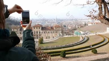 女游客使用智能手机，拍照到都灵城市全景，都灵旅游目的地在意大利。