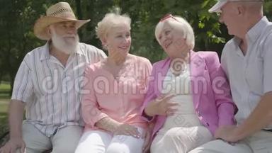 两对可爱的成熟夫妇在<strong>夏天</strong>公园里坐在长凳上聊天和微笑。 老年夫妇双人<strong>约会</strong>