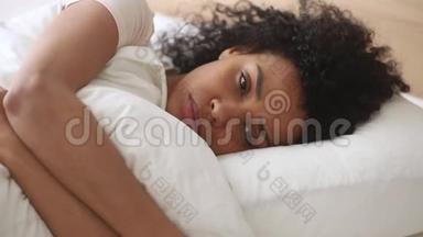 沮丧的非洲女人躺在床上拥<strong>抱枕</strong>头感到不快乐