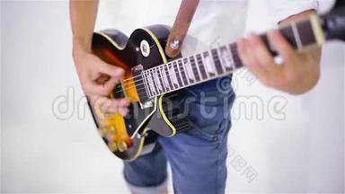 一个人在画室里用白色背景弹吉他，特写