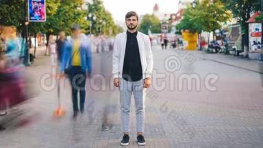 穿着时尚服装的英俊青年站在大城市的街道上，用照相机看着镜头